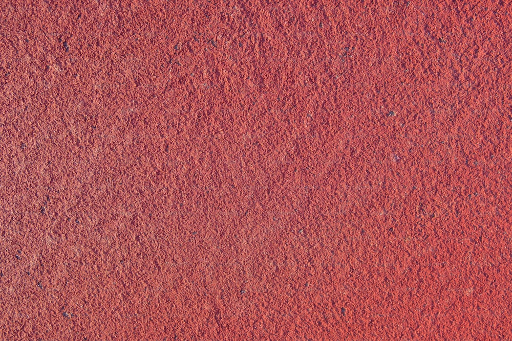 a close up of a red wall with a small patch of dirt