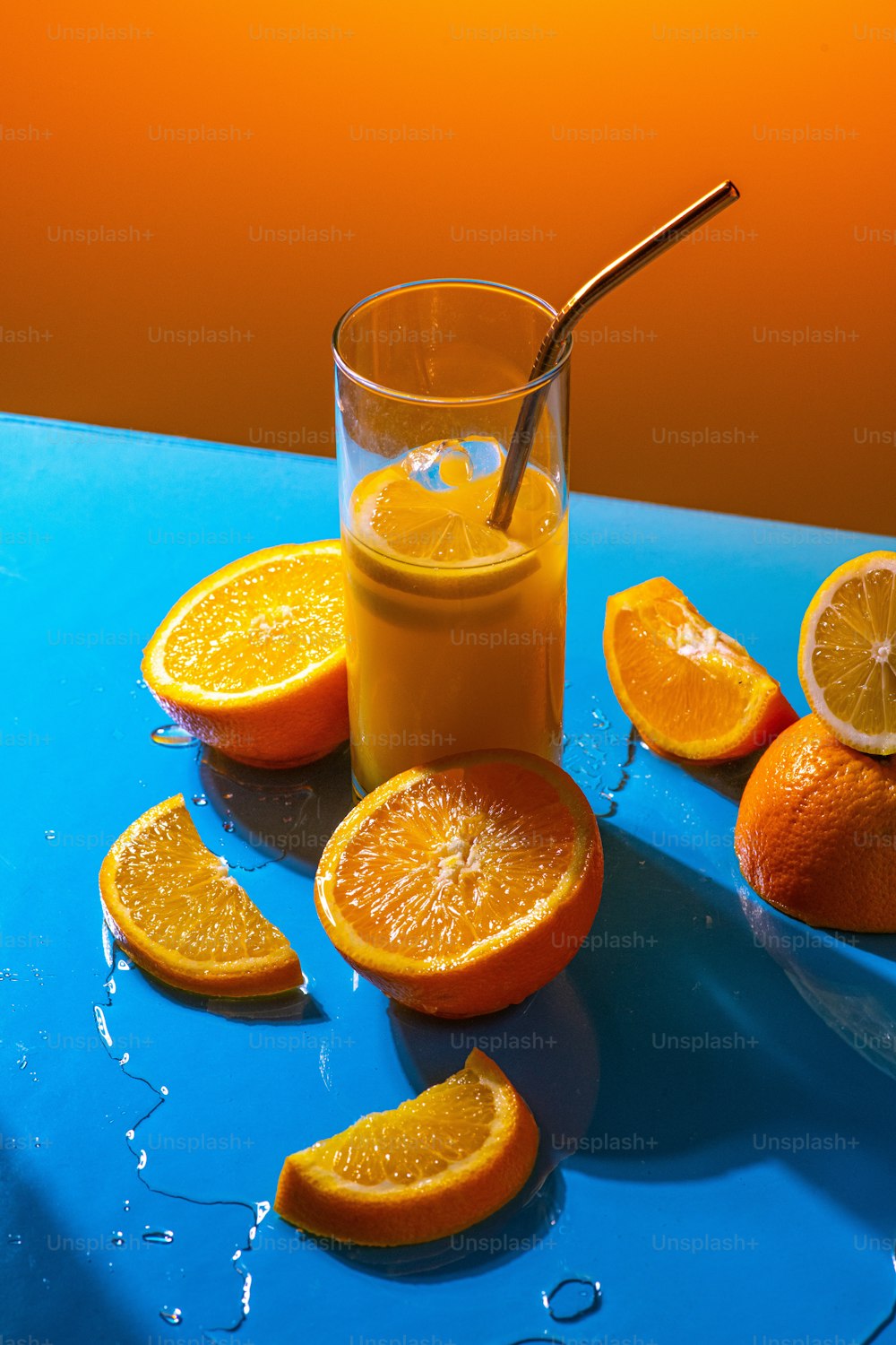 a glass of orange juice next to sliced oranges