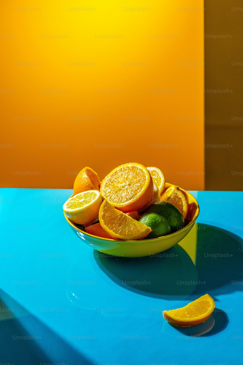 a bowl of oranges and limes on a blue table