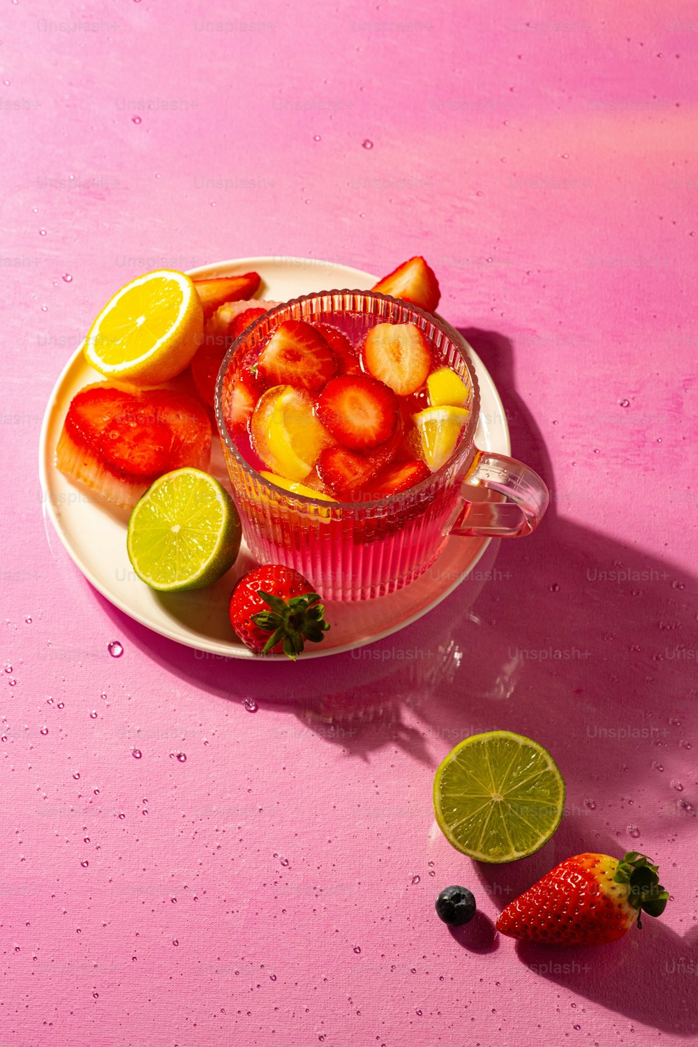 a bowl of fruit with lemons, strawberries, and limes