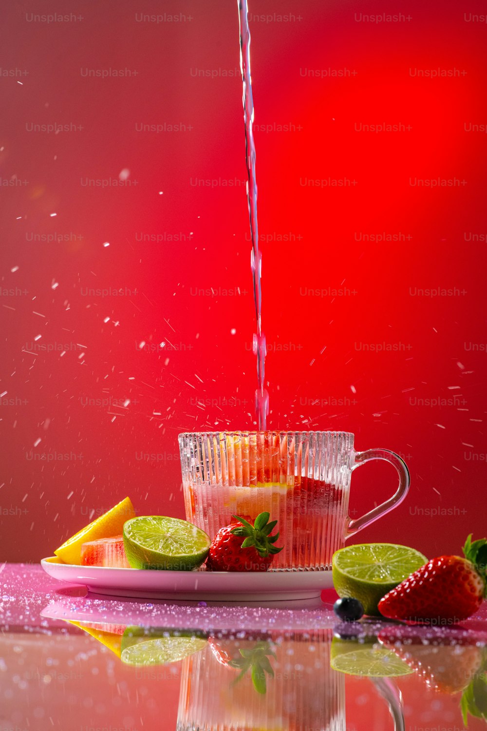 um jarro de água derramando em um copo cheio de frutas