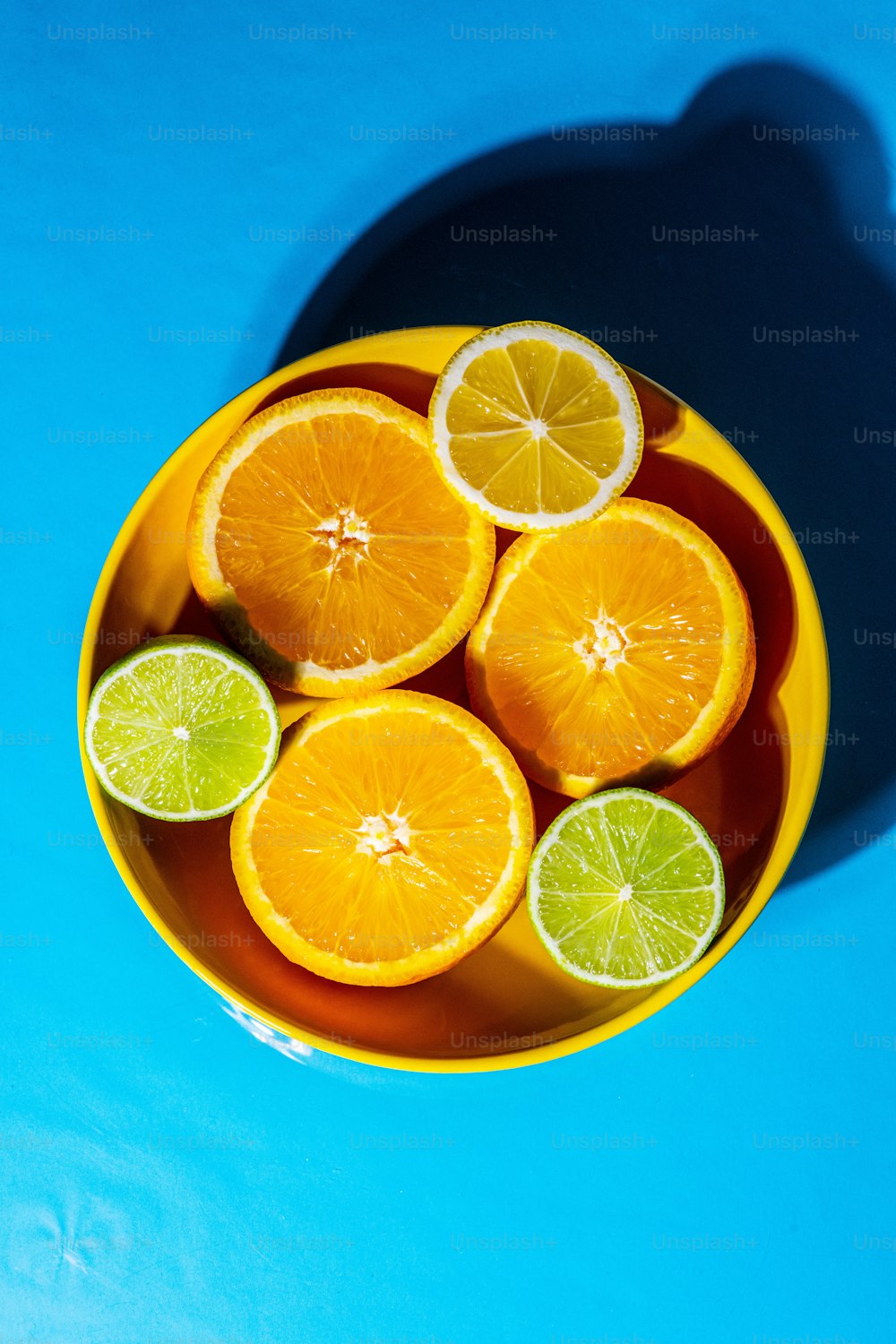 una ciotola gialla piena di arance e lime affettati