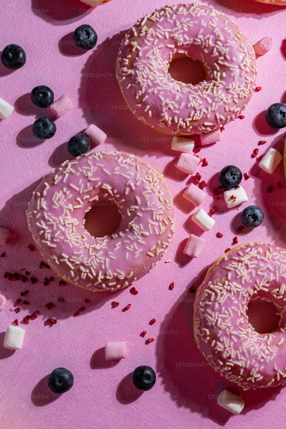 분홍색 표면 위에 앉아있는 도넛 두 개