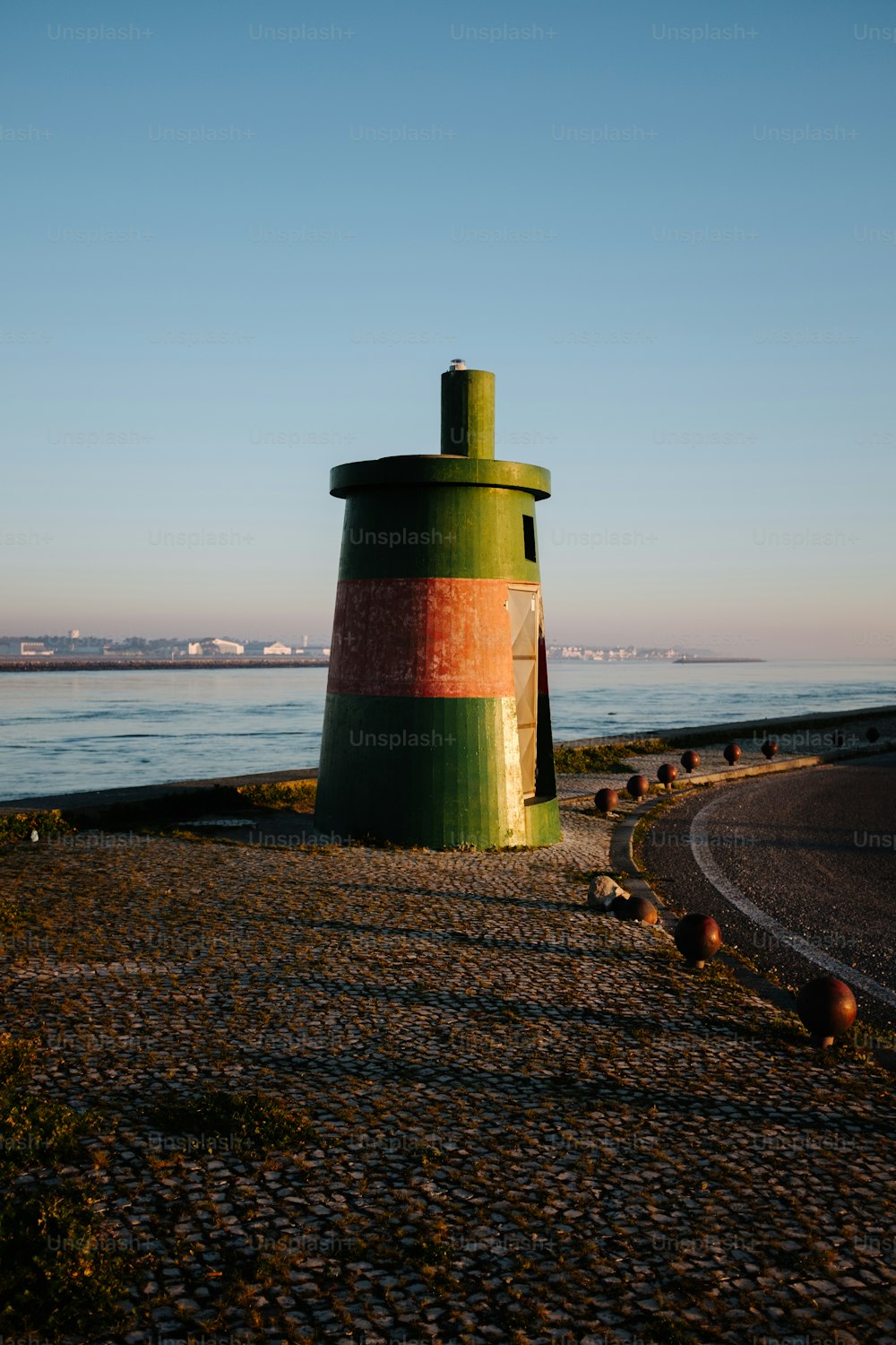 a green and red lighthouse sitting on the side of a road