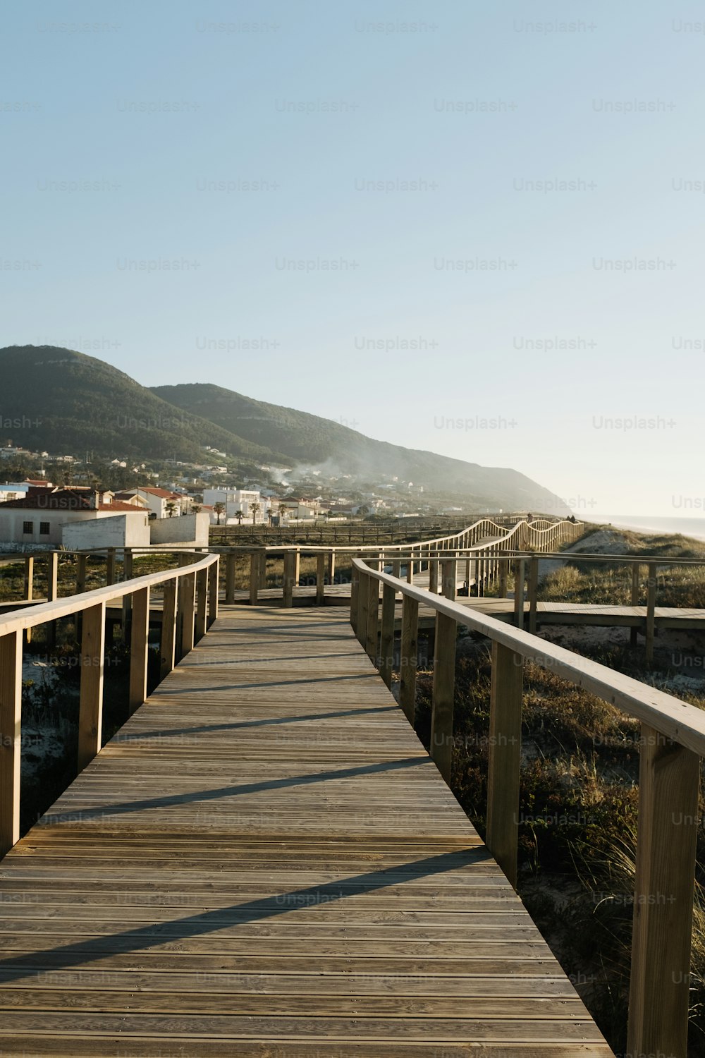 a wooden walkway leading to a beach with a mountain in the background