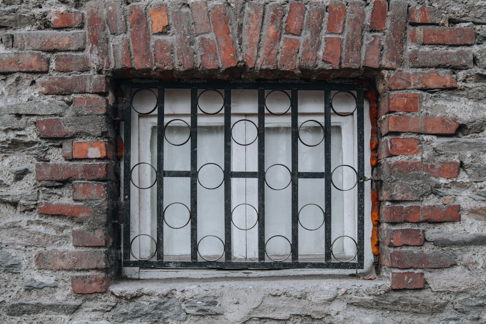 a window in a brick wall with bars on it