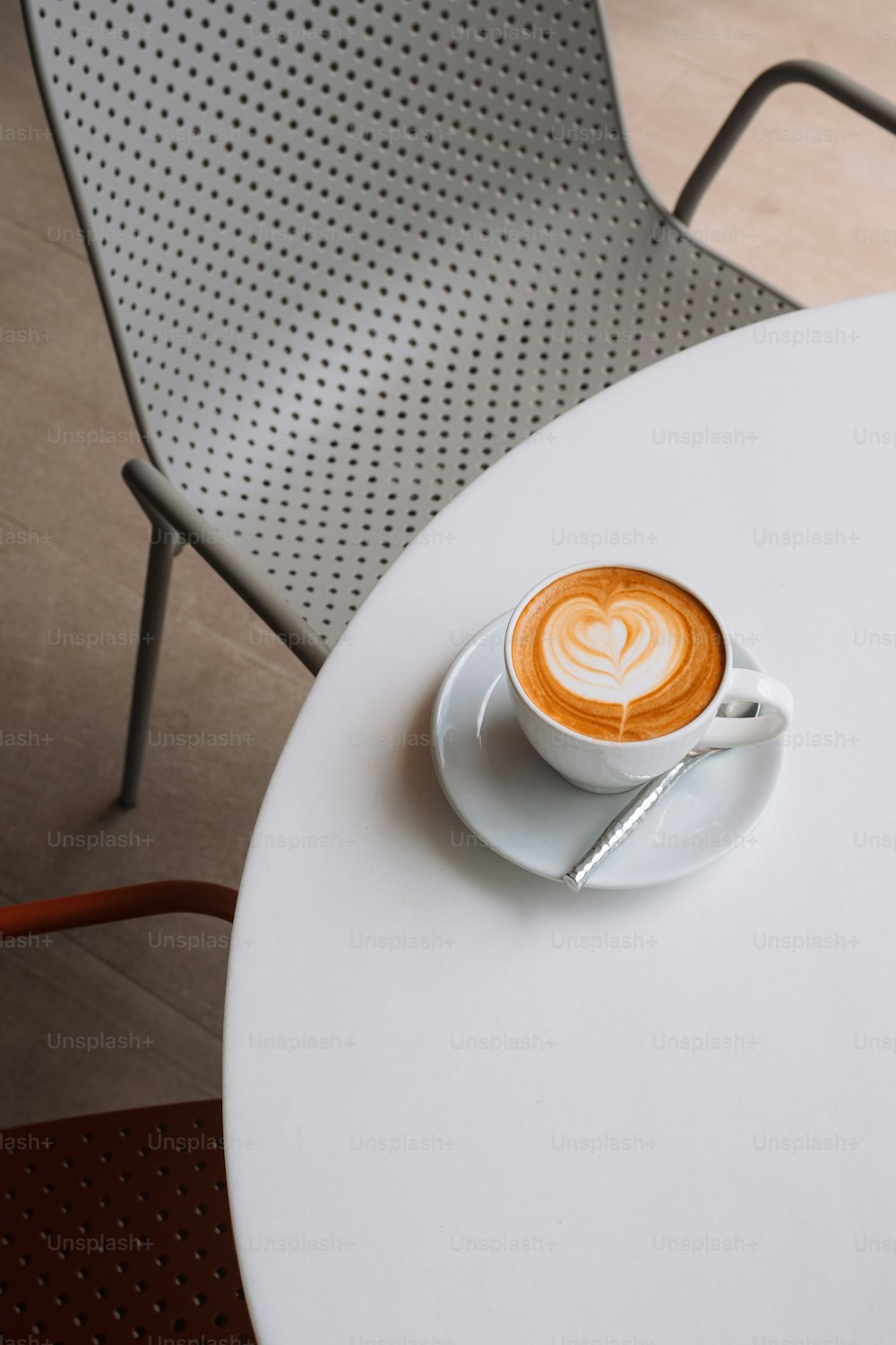 a cappuccino sits on a saucer on a white table