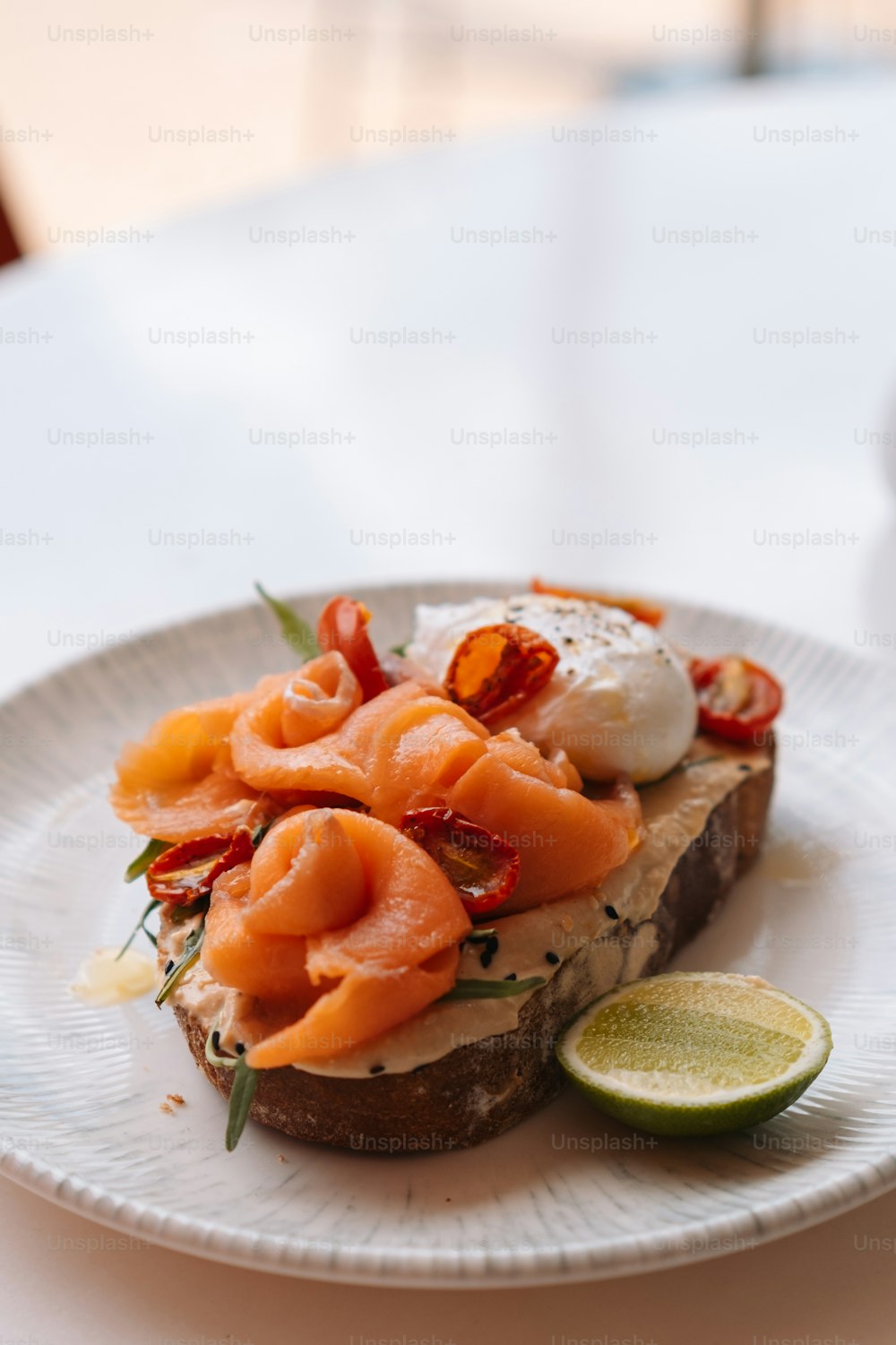a white plate topped with a piece of bread covered in salmon