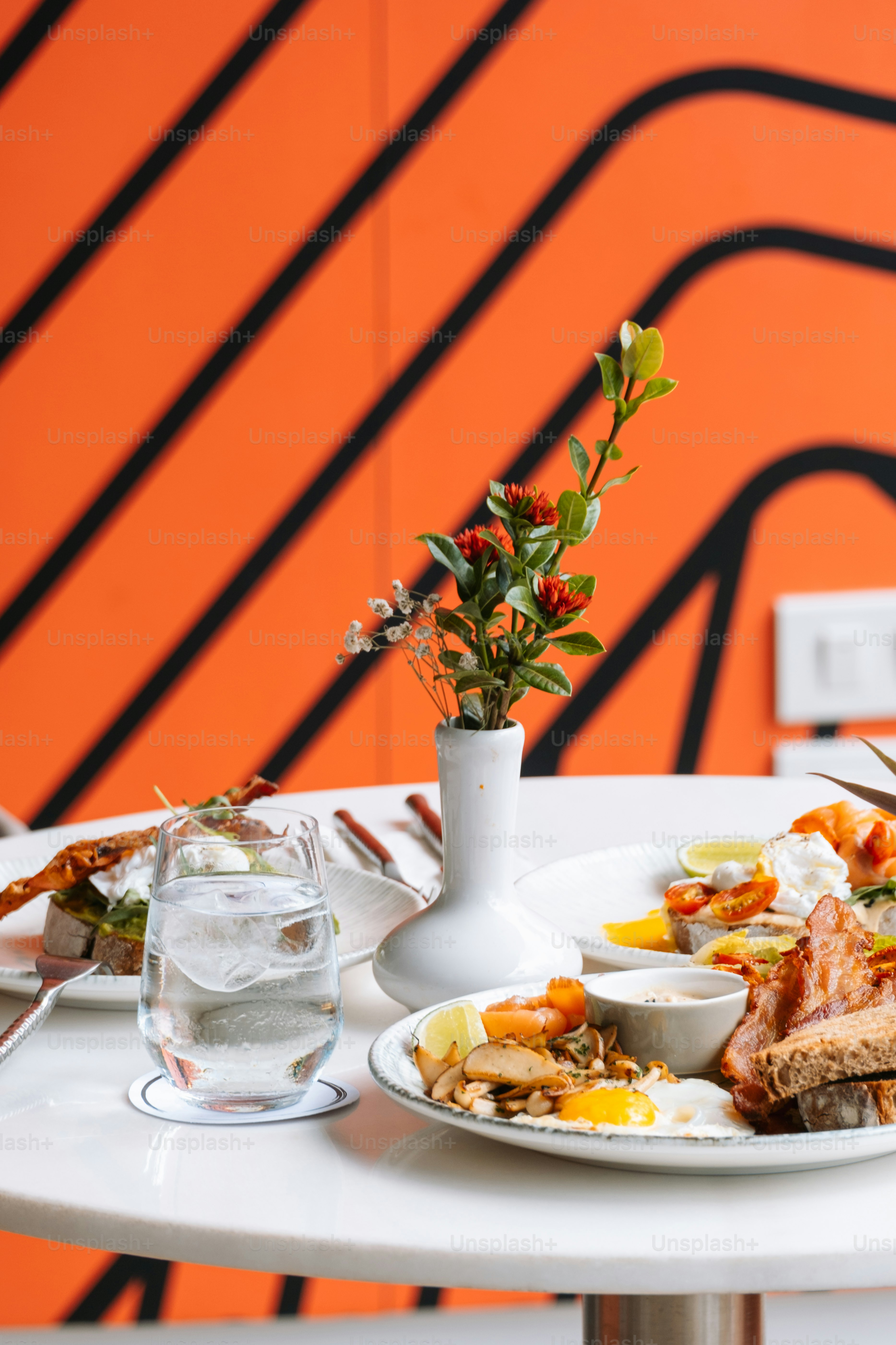 a white table topped with a plate of food and a vase filled with flowers