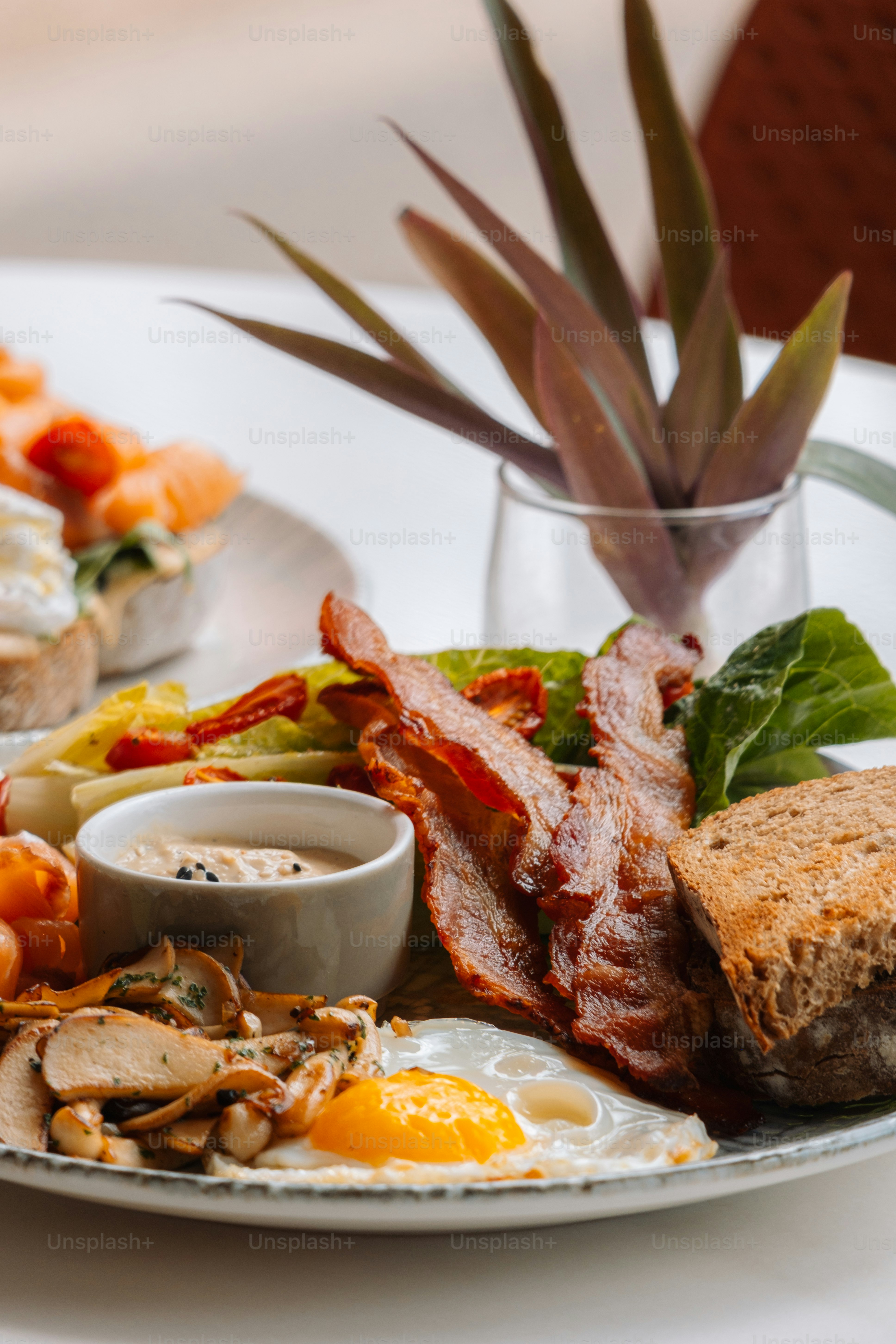 une assiette blanche garnie d’œufs, de bacon et de pain grillé