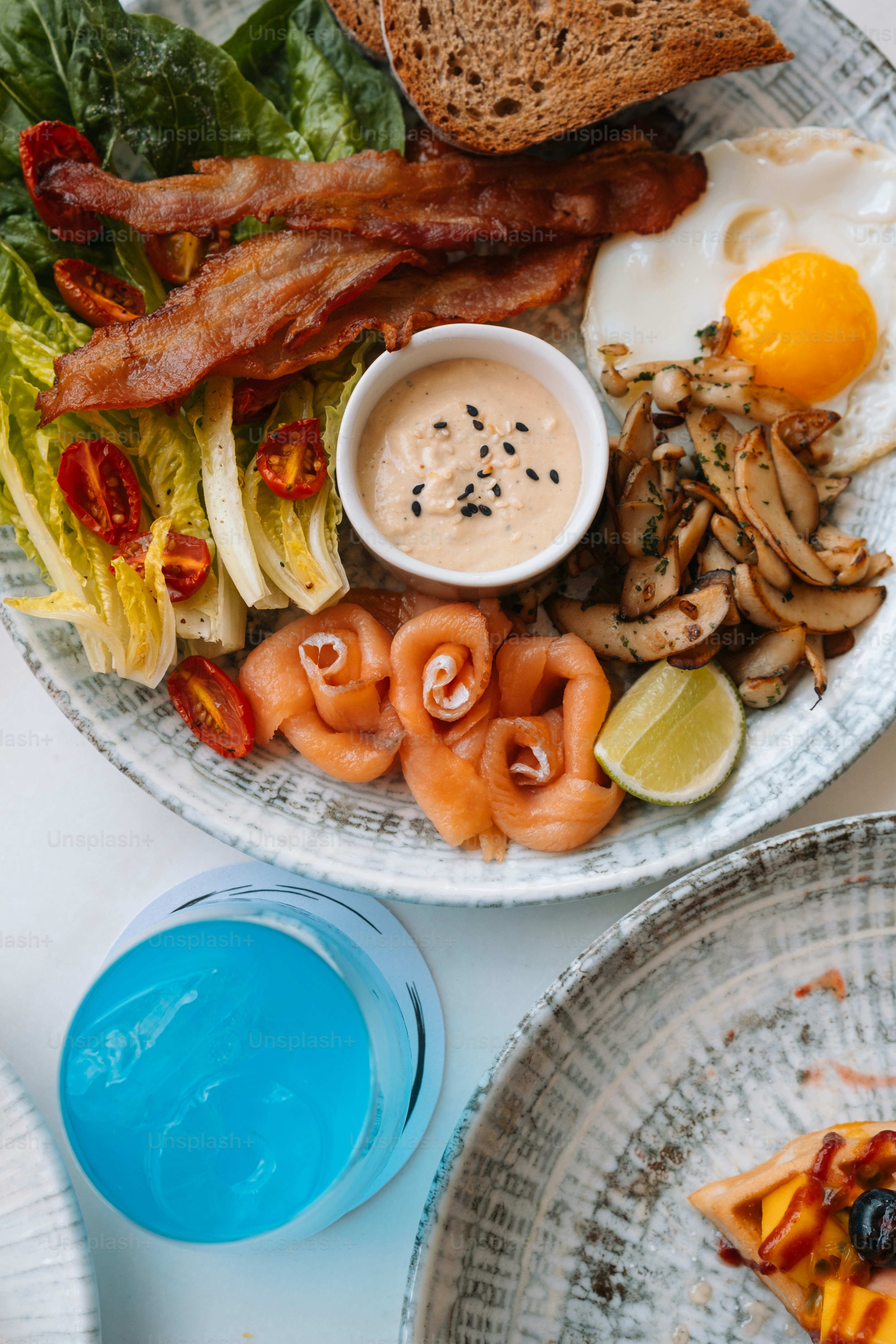 Un plato de comida que incluye huevos, tocino, tostadas y ensalada