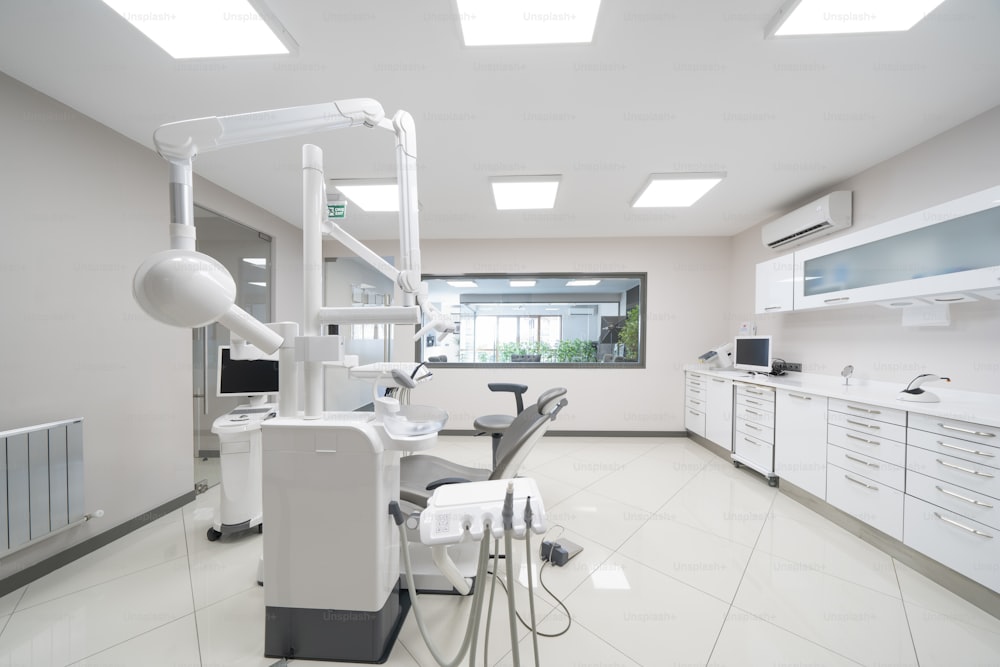 uma sala com uma cadeira de dentista, luzes e outros equipamentos médicos