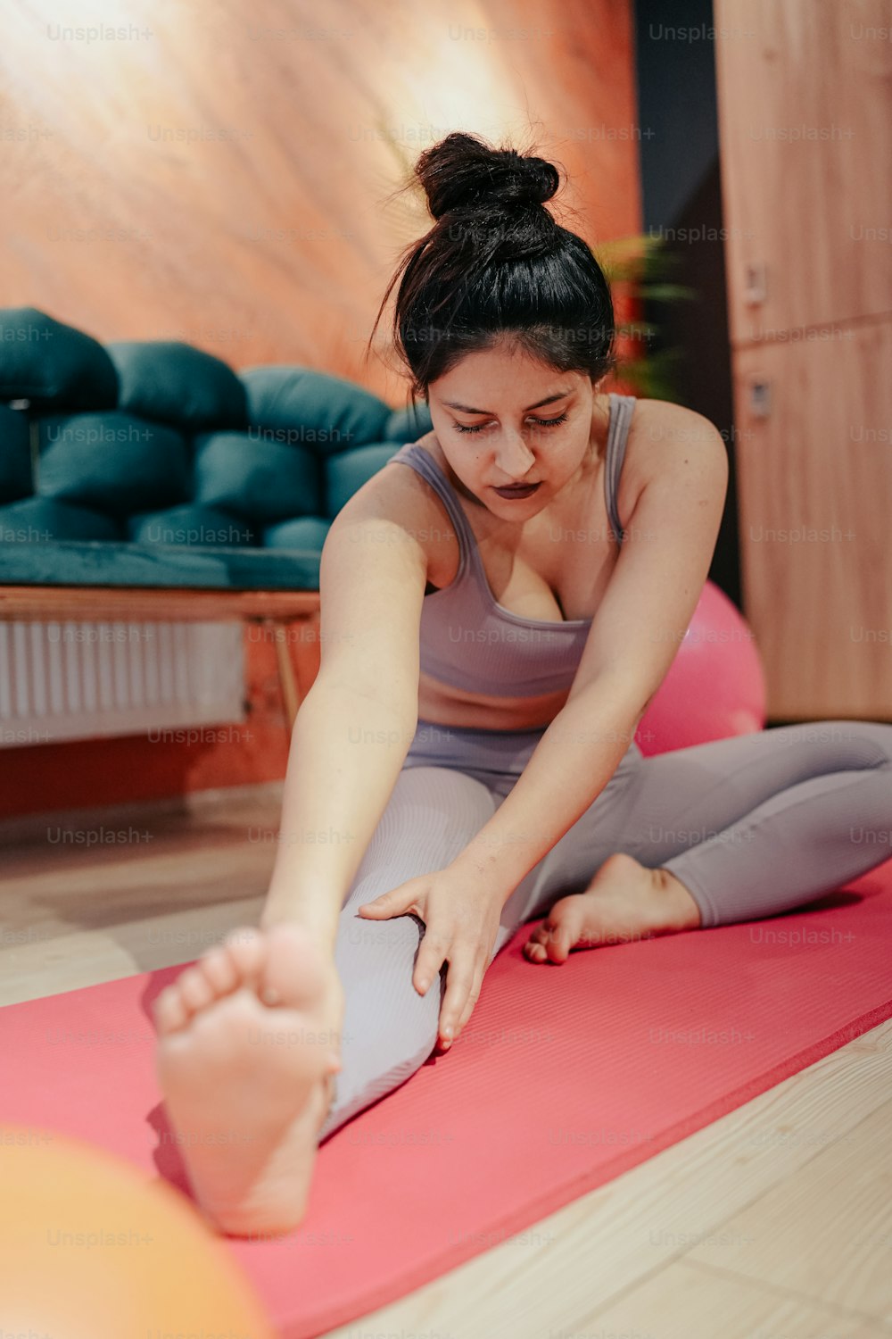 Una mujer sentada en una esterilla de yoga estirando las piernas