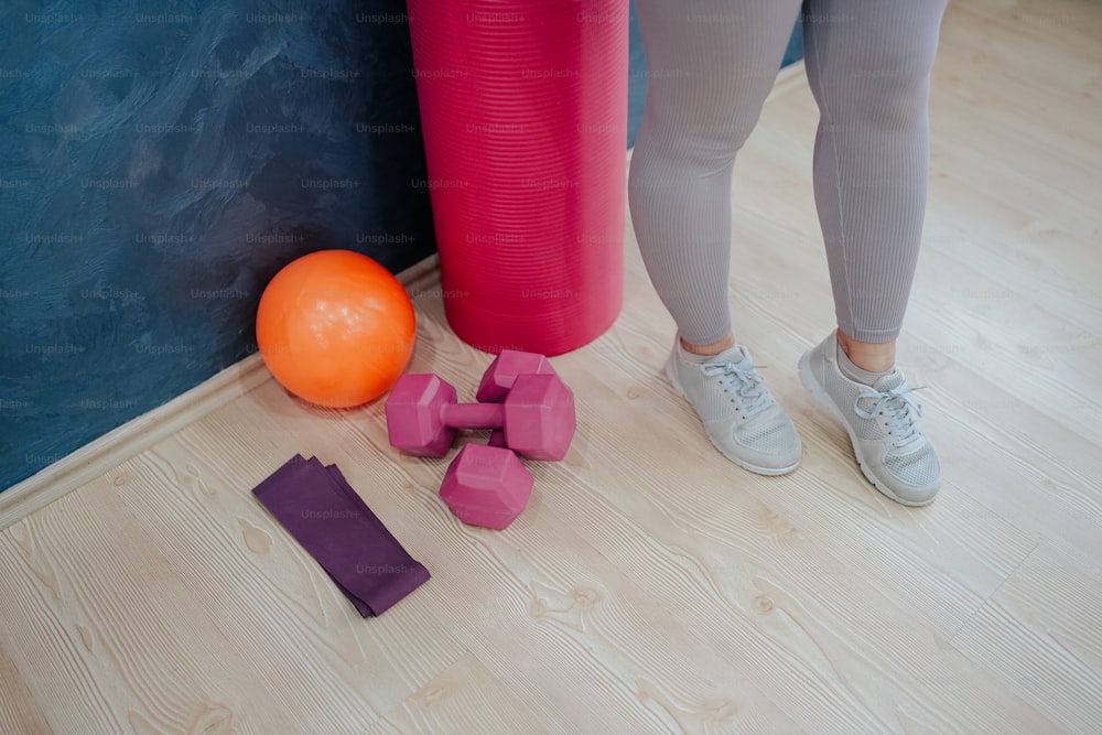 a person standing next to a yoga mat and a ball