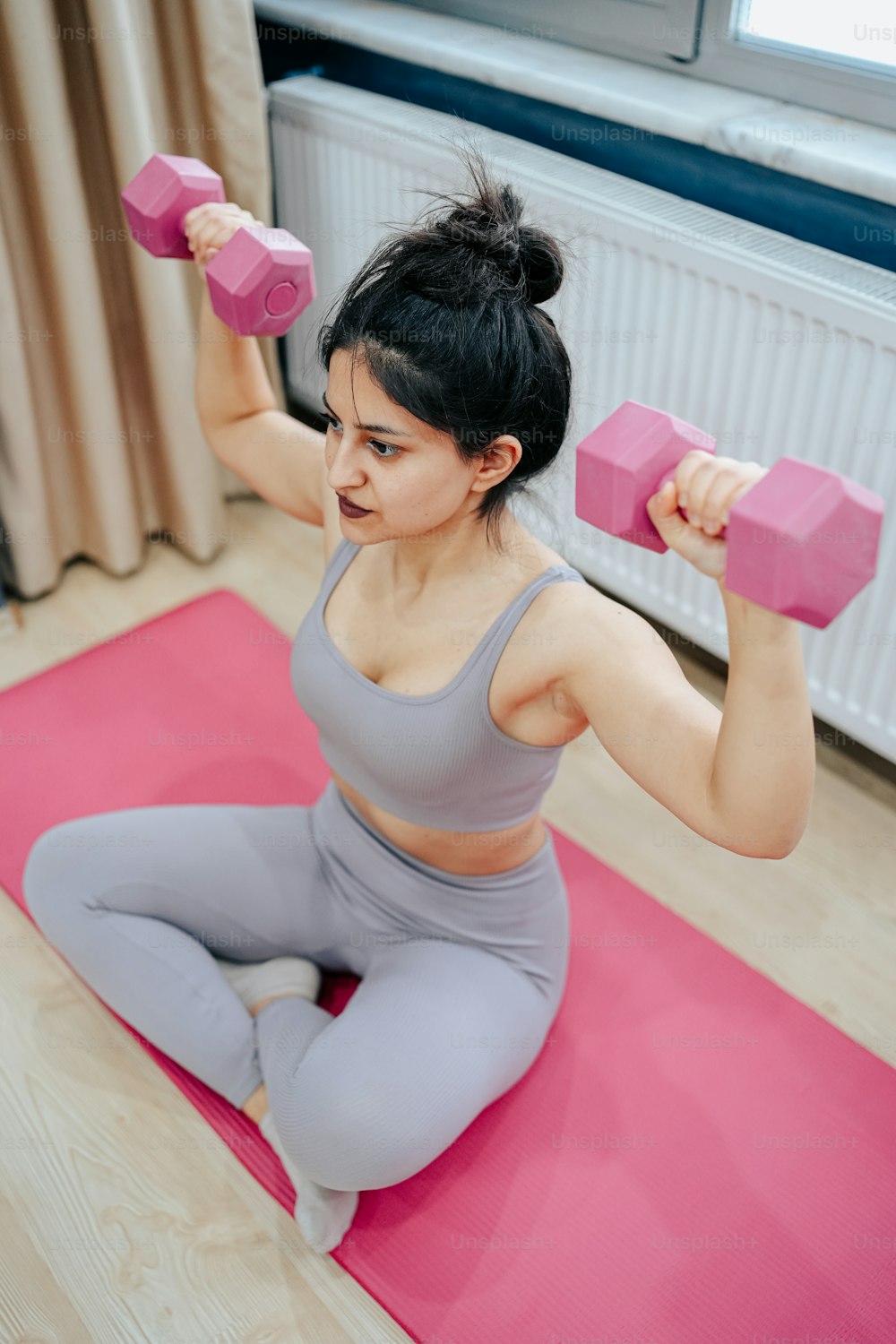 Una mujer está haciendo ejercicios con mancuernas rosadas