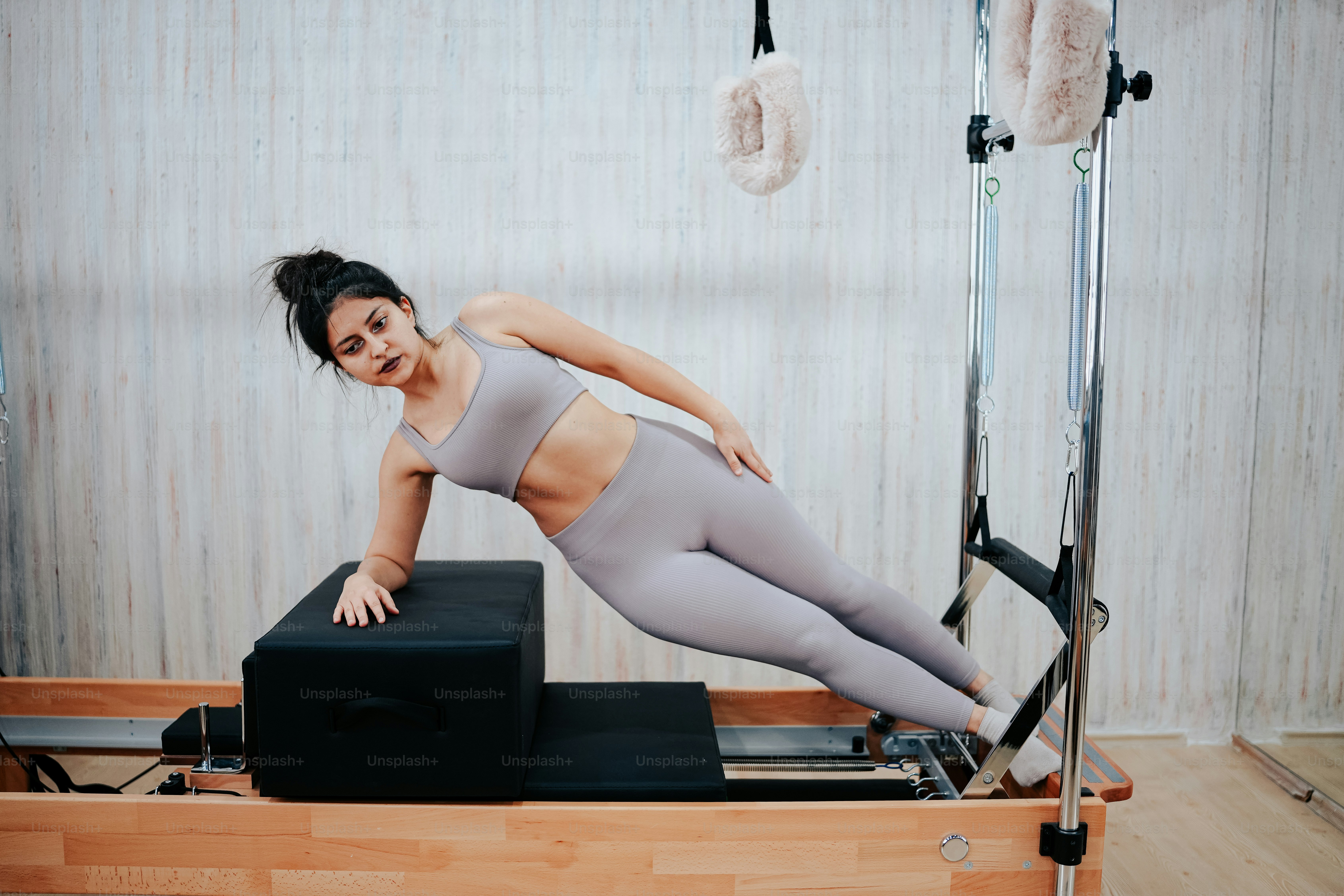A woman in a gray top is doing pivots on a rowing machine photo ...