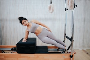 a woman in a gray top is doing pivots on a rowing machine