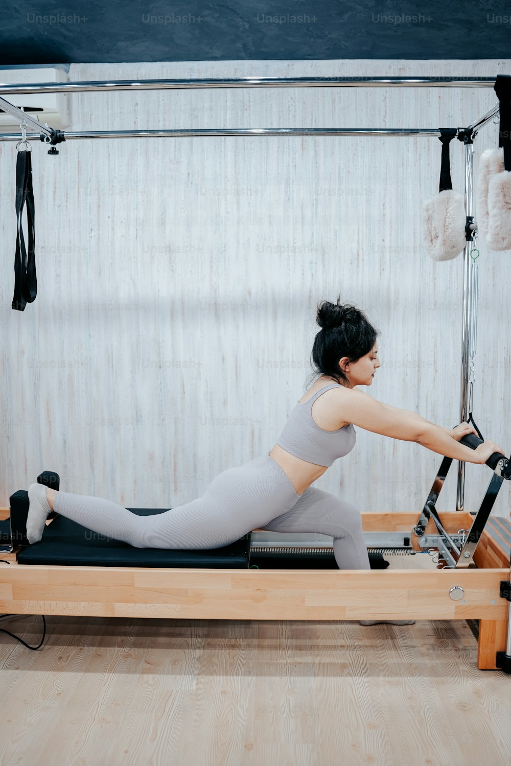 a woman in a gray top is on a rowing machine