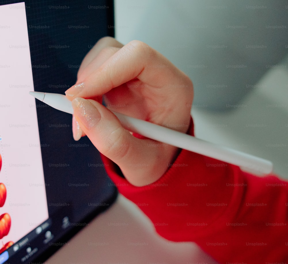 a person holding a white pen in front of a computer screen