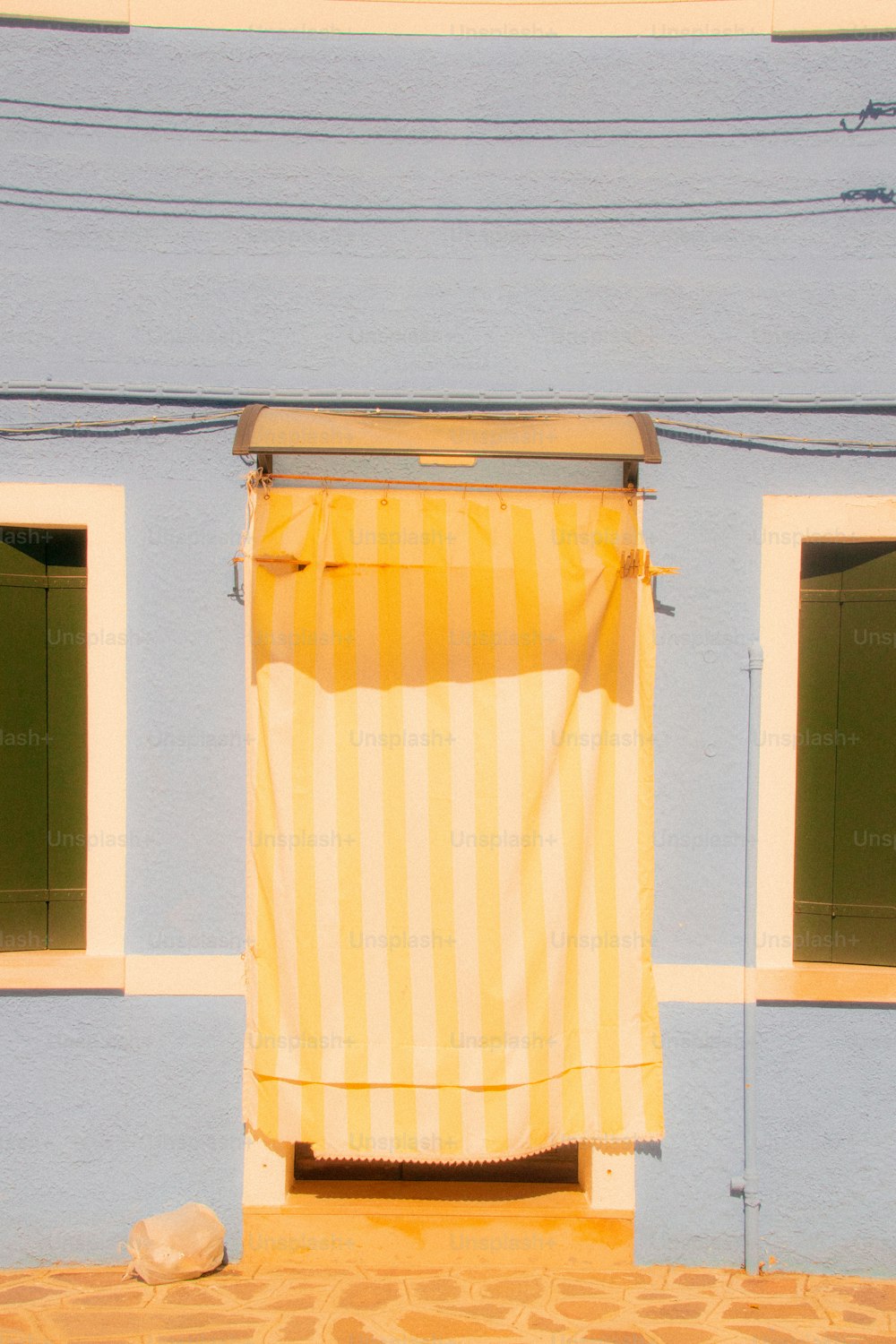 Un edificio azul con una cortina de rayas amarillas y blancas