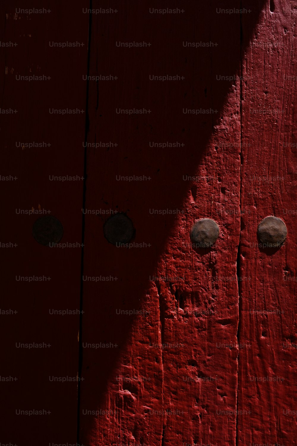 a close up of a red door with three knobs
