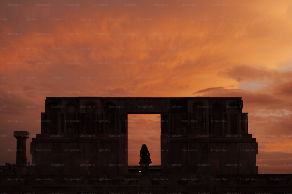 a silhouette of a person standing in front of a gate