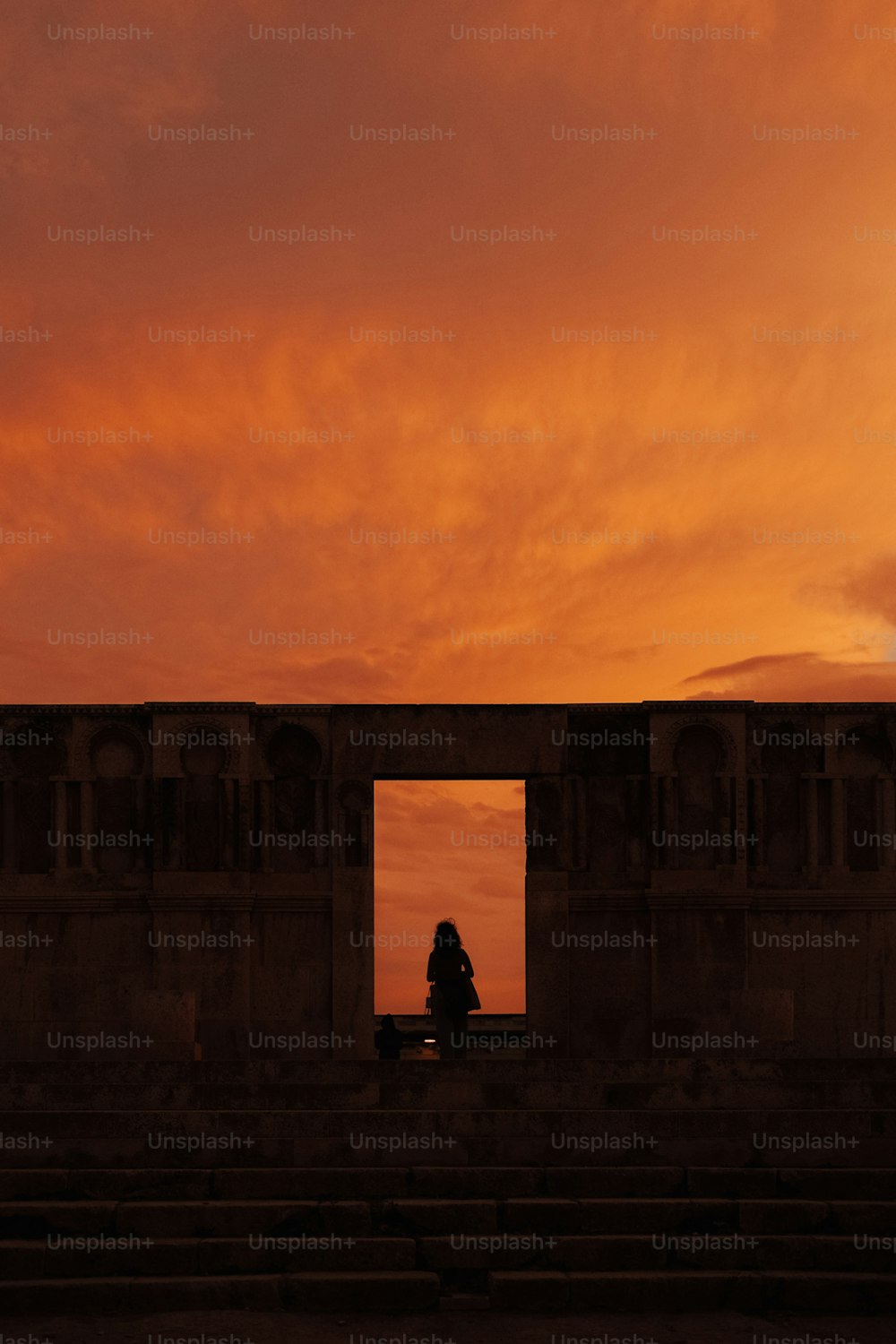 uma pessoa sentada em um banco assistindo ao pôr do sol