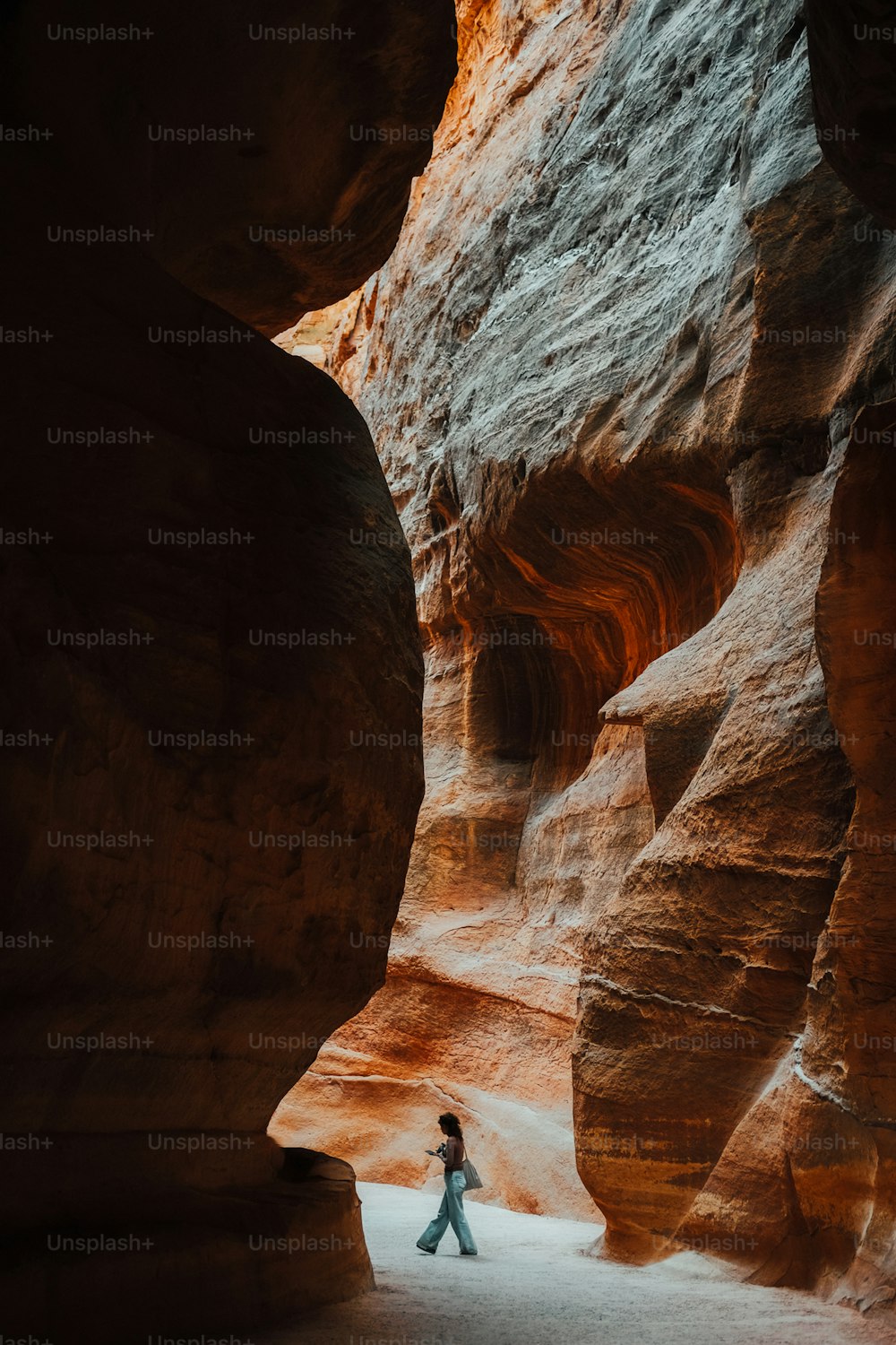 a person walking through a narrow slot in a canyon