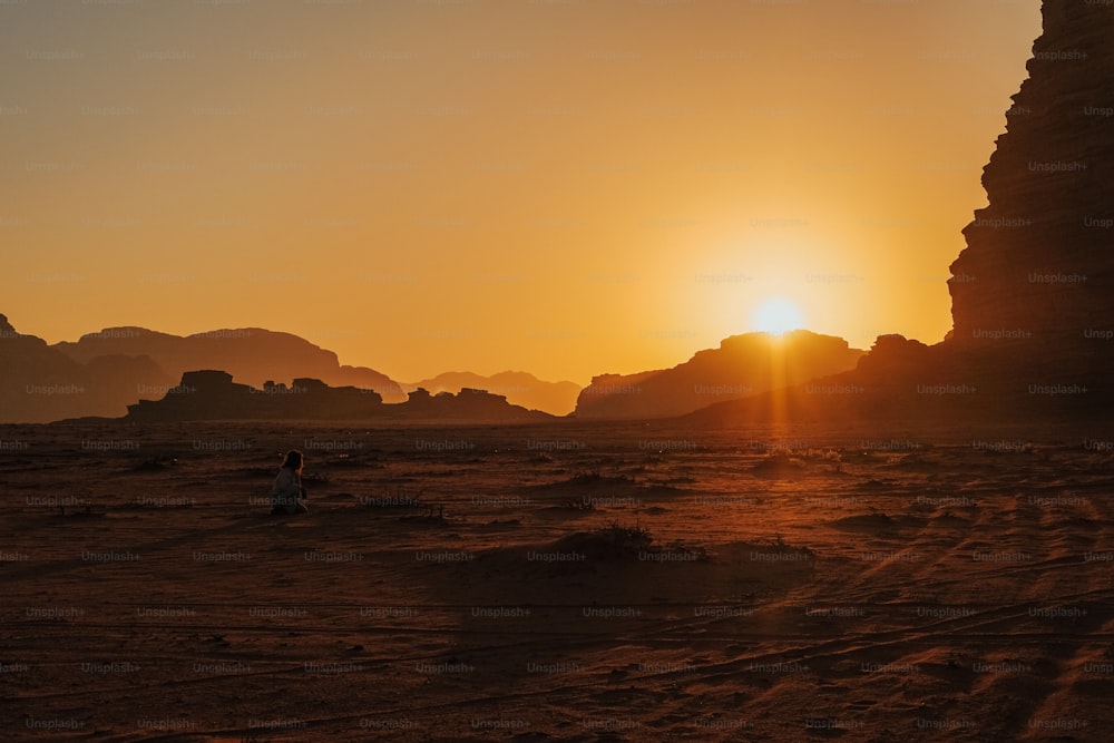 a person walking in the desert at sunset