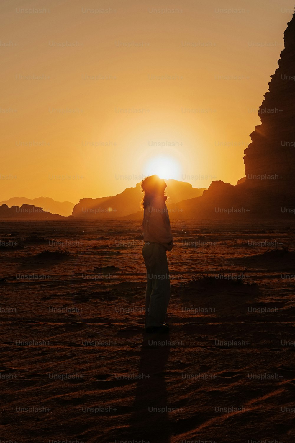 Eine Person, die bei Sonnenuntergang mitten in einer Wüste steht
