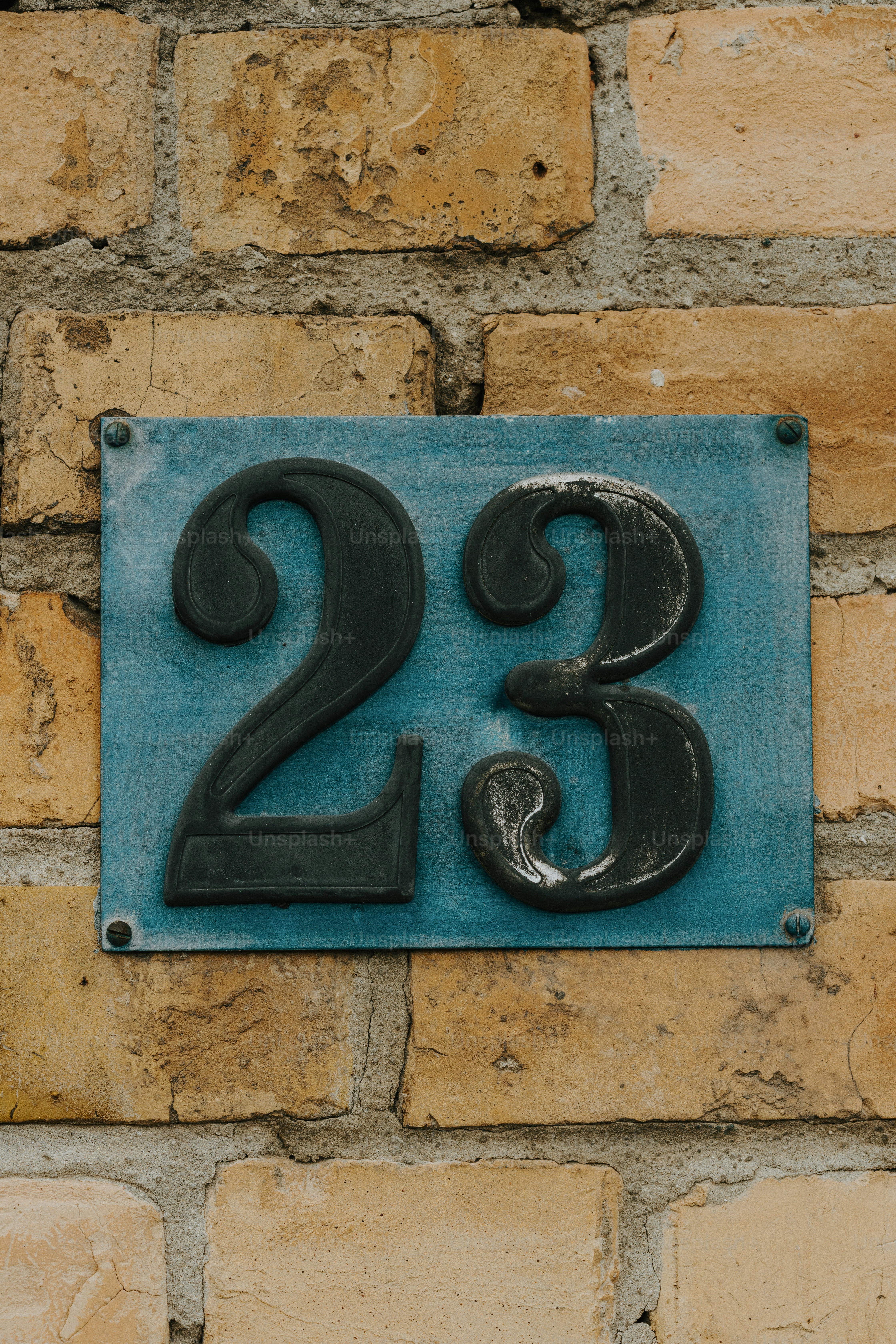 a blue and black sign on a brick wall