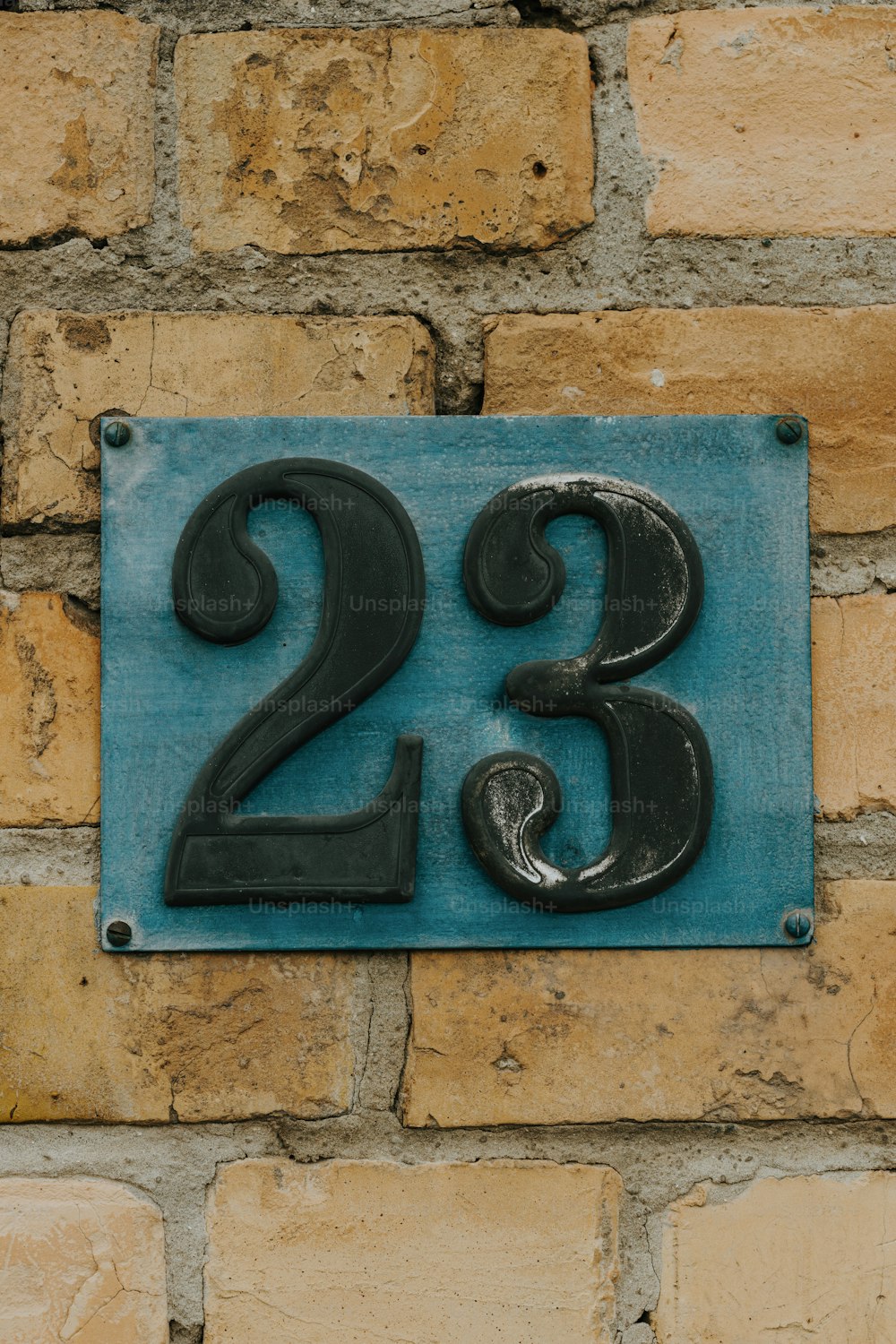 a blue and black sign on a brick wall