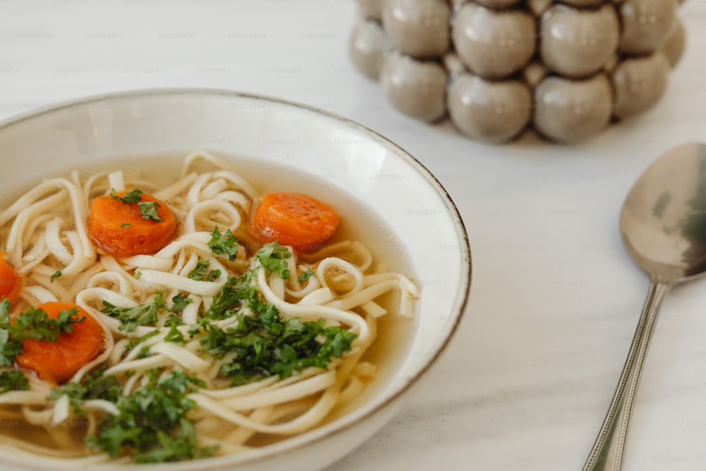 a bowl of noodles with carrots and parsley