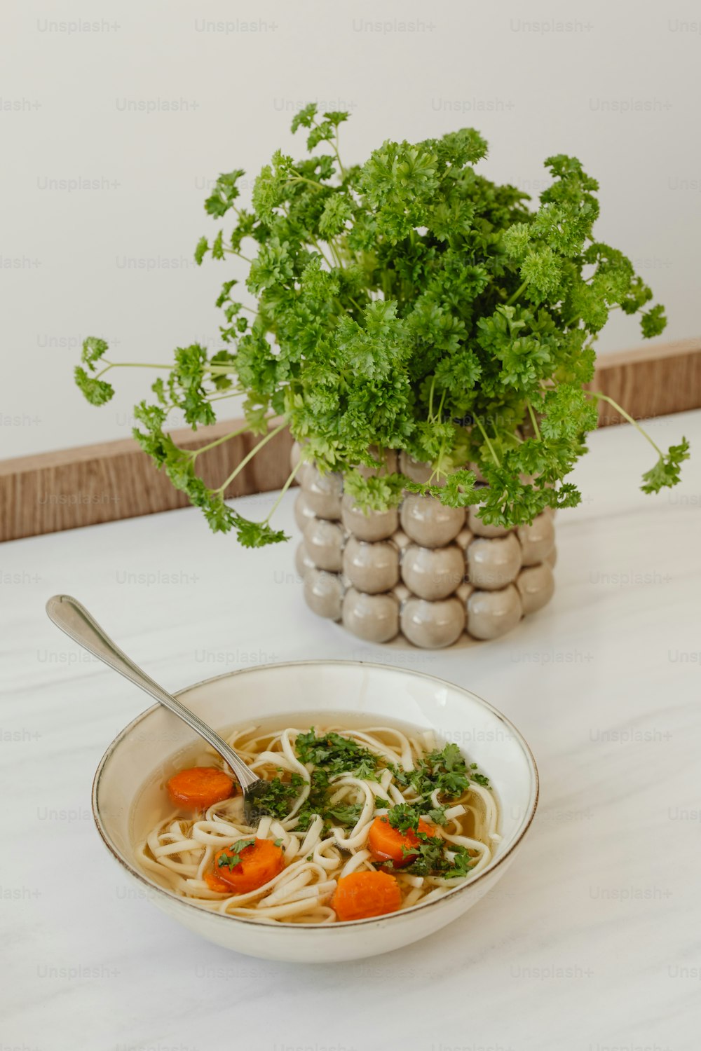 a bowl of soup with carrots and parsley