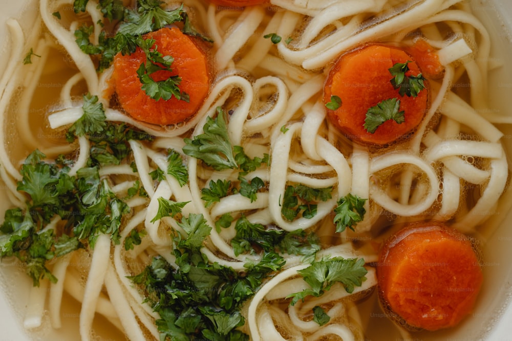 a bowl of noodles with carrots and parsley