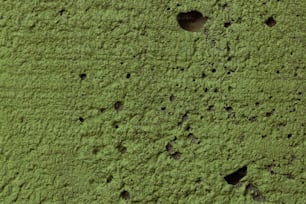 un primo piano di un muro verde con buchi in esso