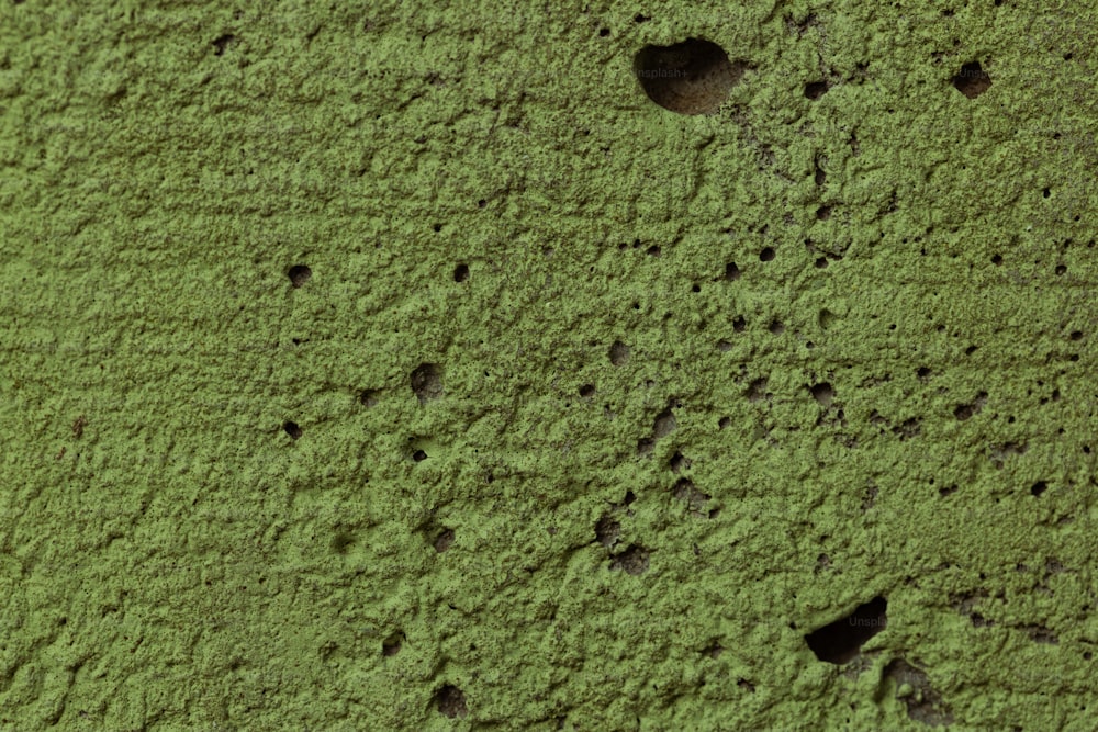 a close up of a green wall with holes in it