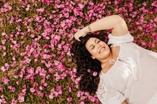 a woman laying in a field of pink flowers