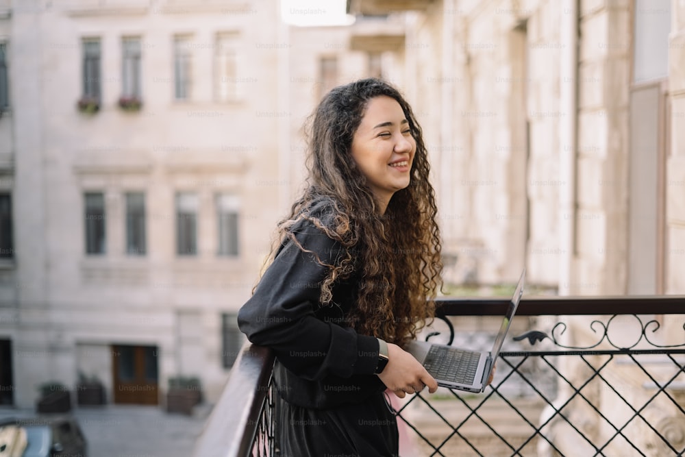 a woman standing on a balcony with a laptop