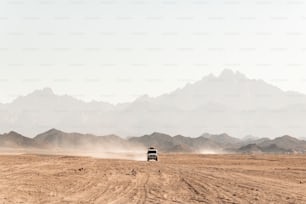 a truck driving down a dirt road in the desert