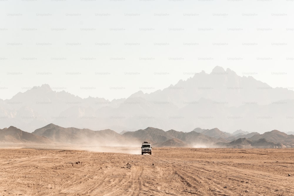 a truck driving down a dirt road in the desert