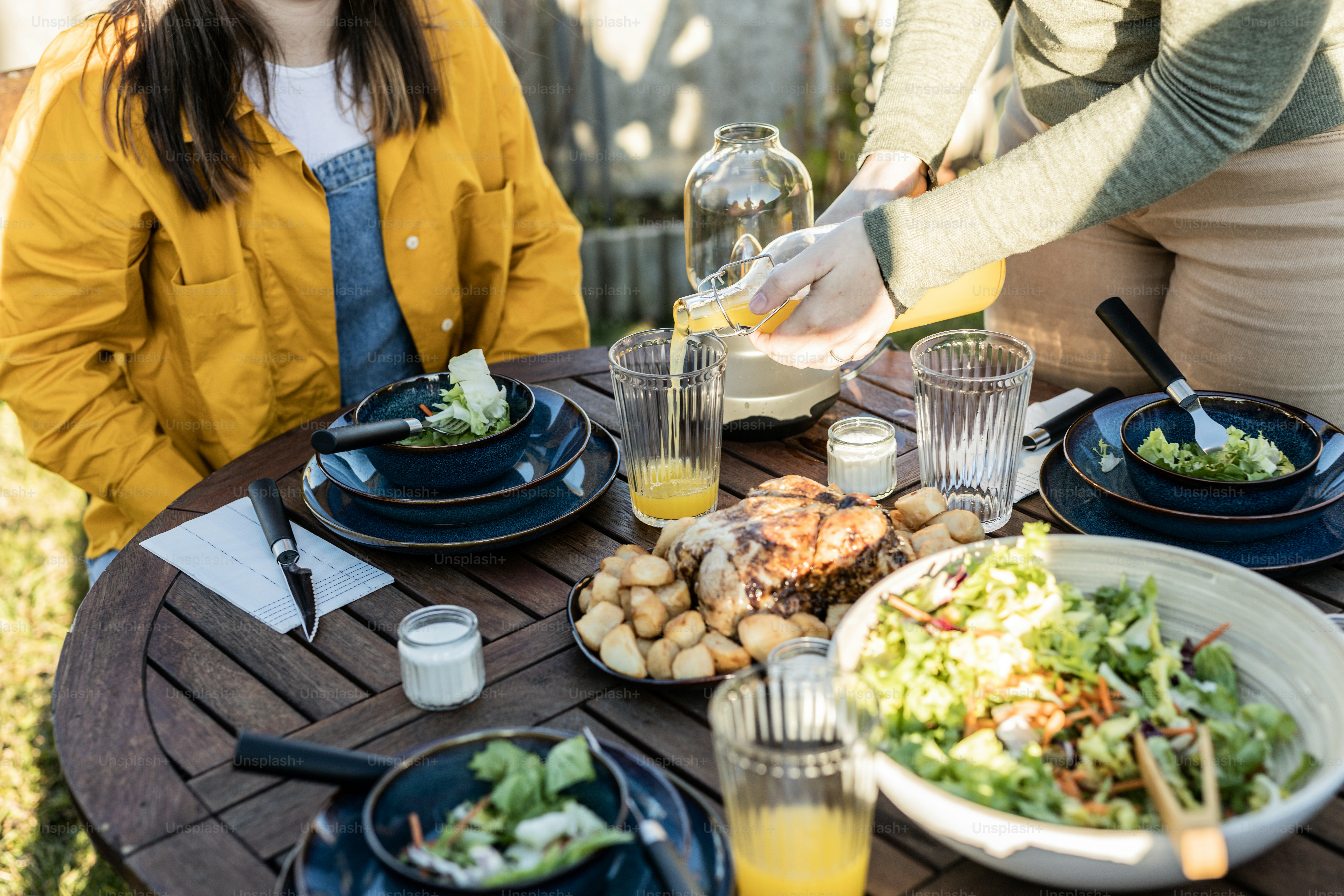 a group of people sitting around a table with plates of food