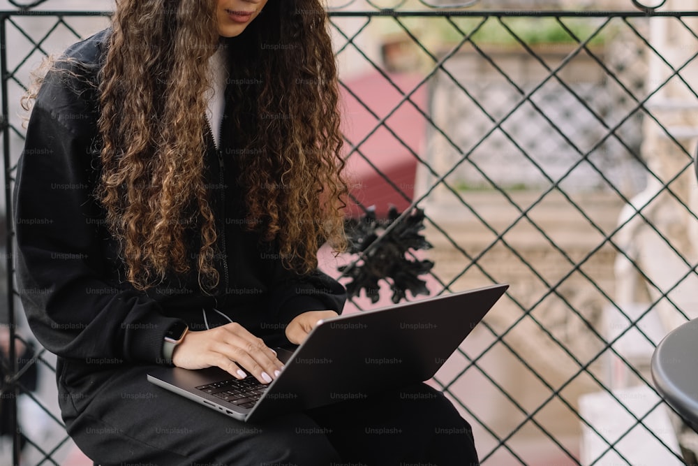 노트북 컴퓨터를 사��용하여 벤치에 앉아 있는 여자