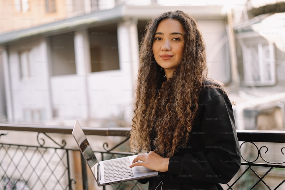 a woman standing on a balcony with a laptop