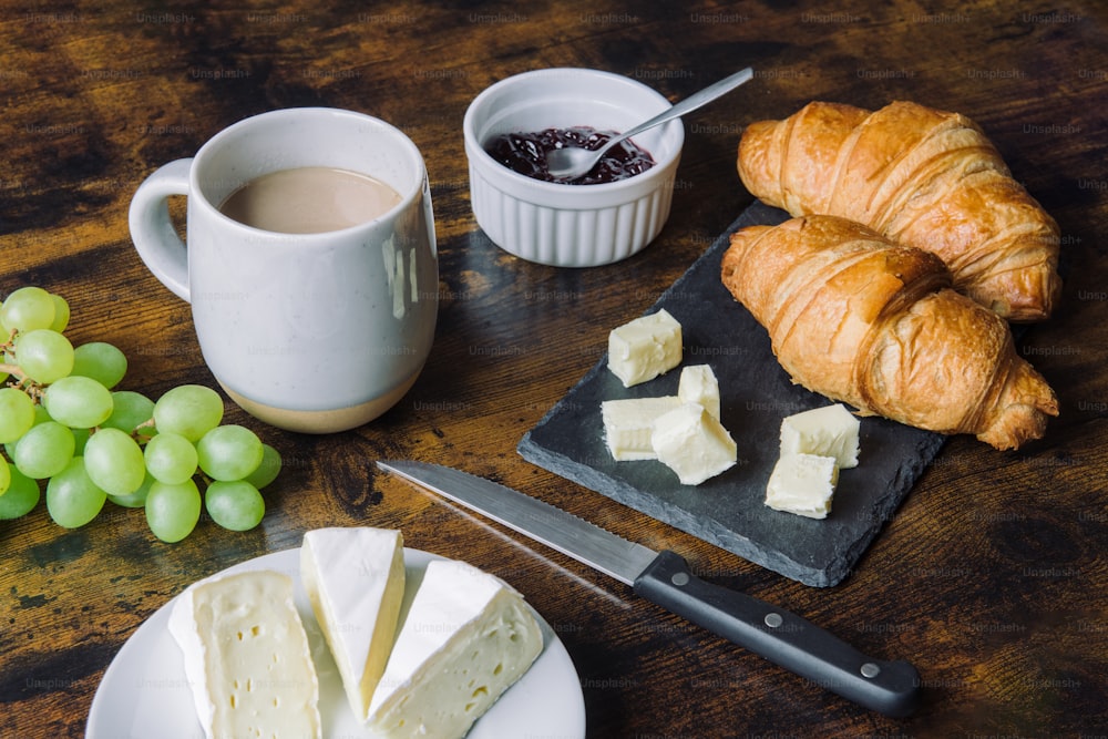 Croissants, Käse, Trauben und eine Tasse Kaffee auf dem Tisch
