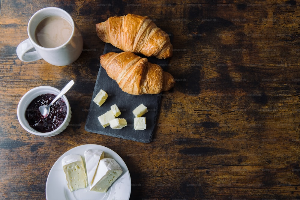 croissants, butter, and jam are on a table