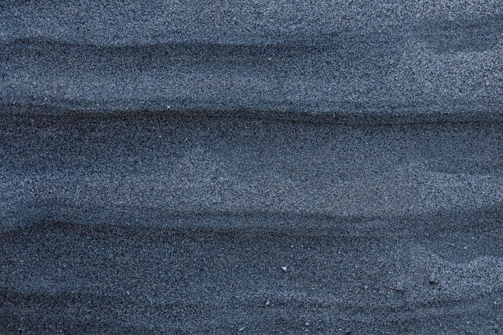 a close up of sand and water with a blue sky in the background