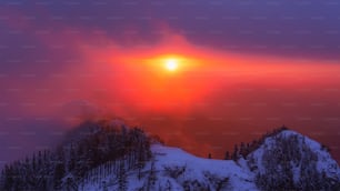 Die Sonne geht über einem verschneiten Berg unter