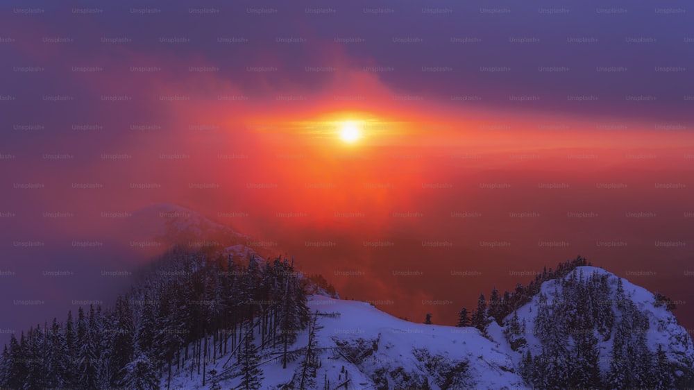 o sol está se pondo sobre uma montanha nevada