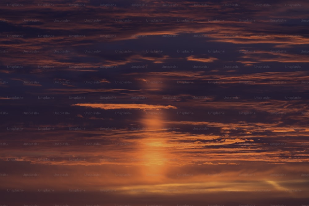 a plane flying in the sky at sunset